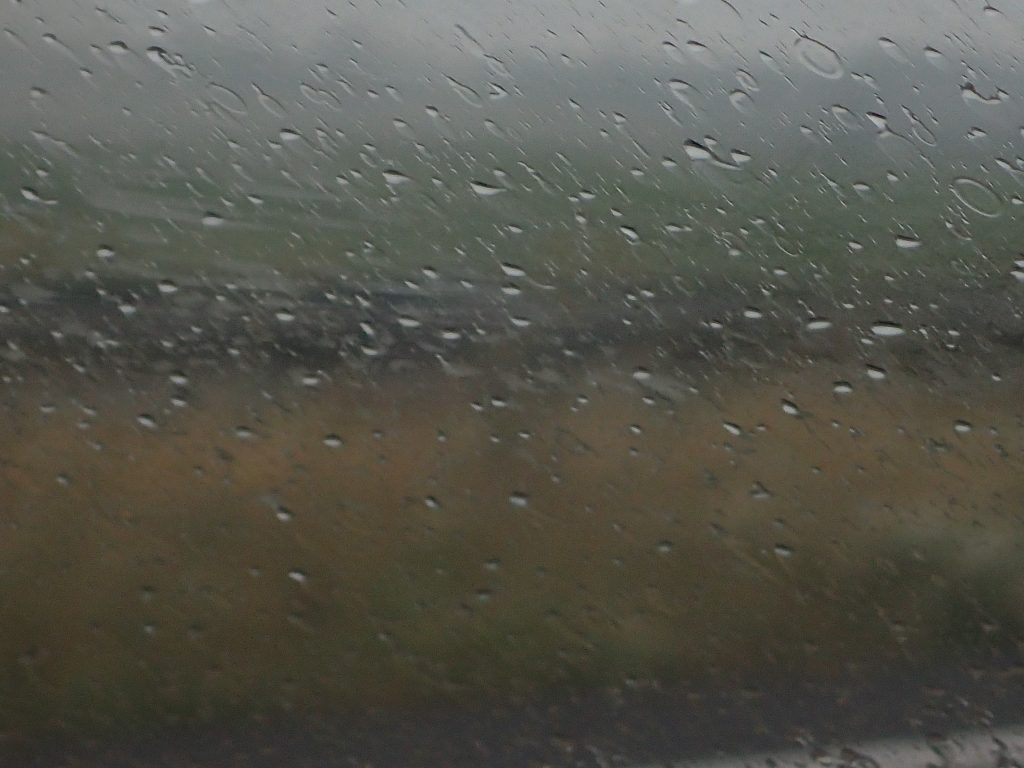 Regen regen en nog eens regen, met een landschap op de achtergrond.